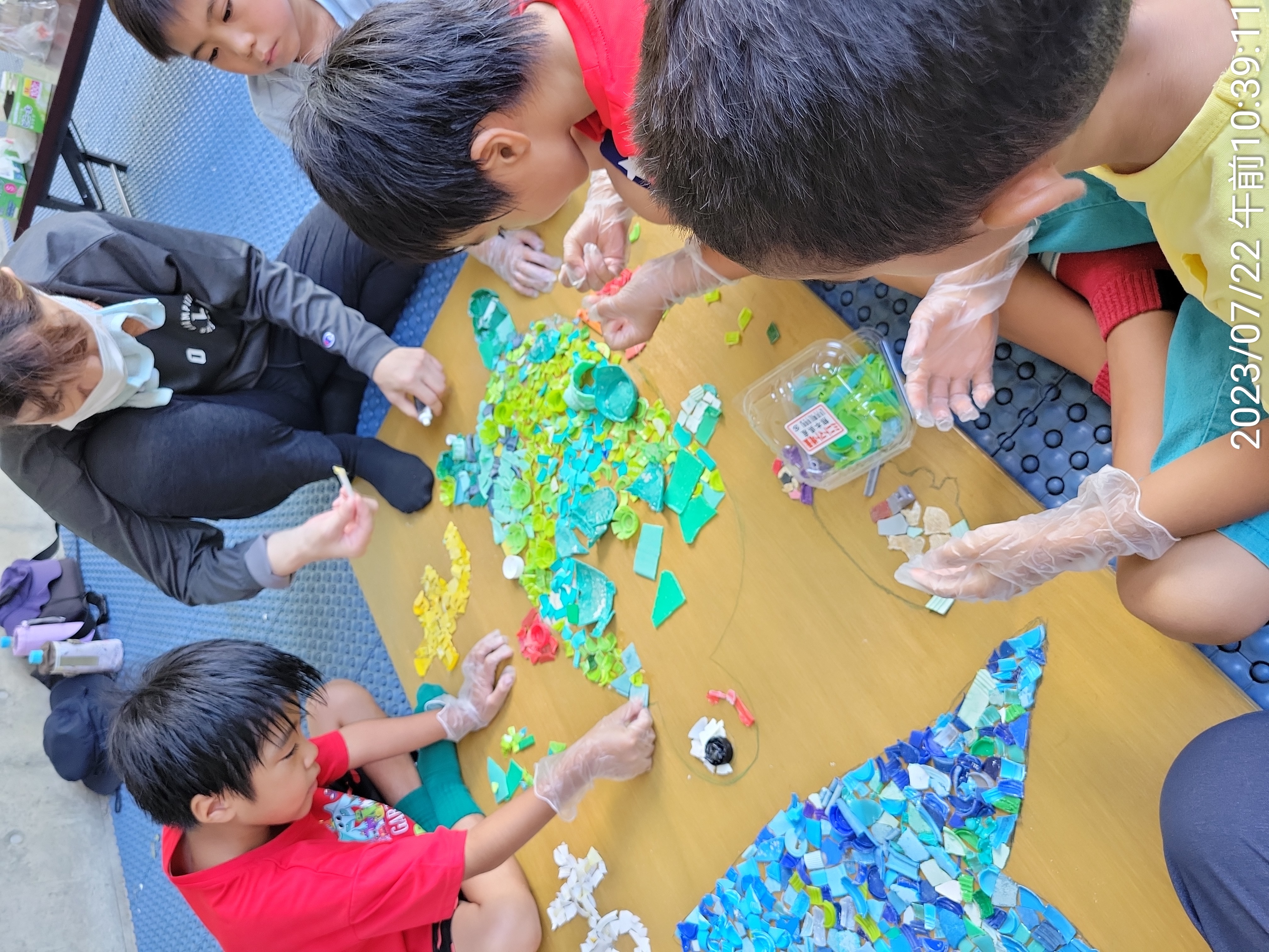 ウミガメと魚の絵をプラごみで作り看板にします